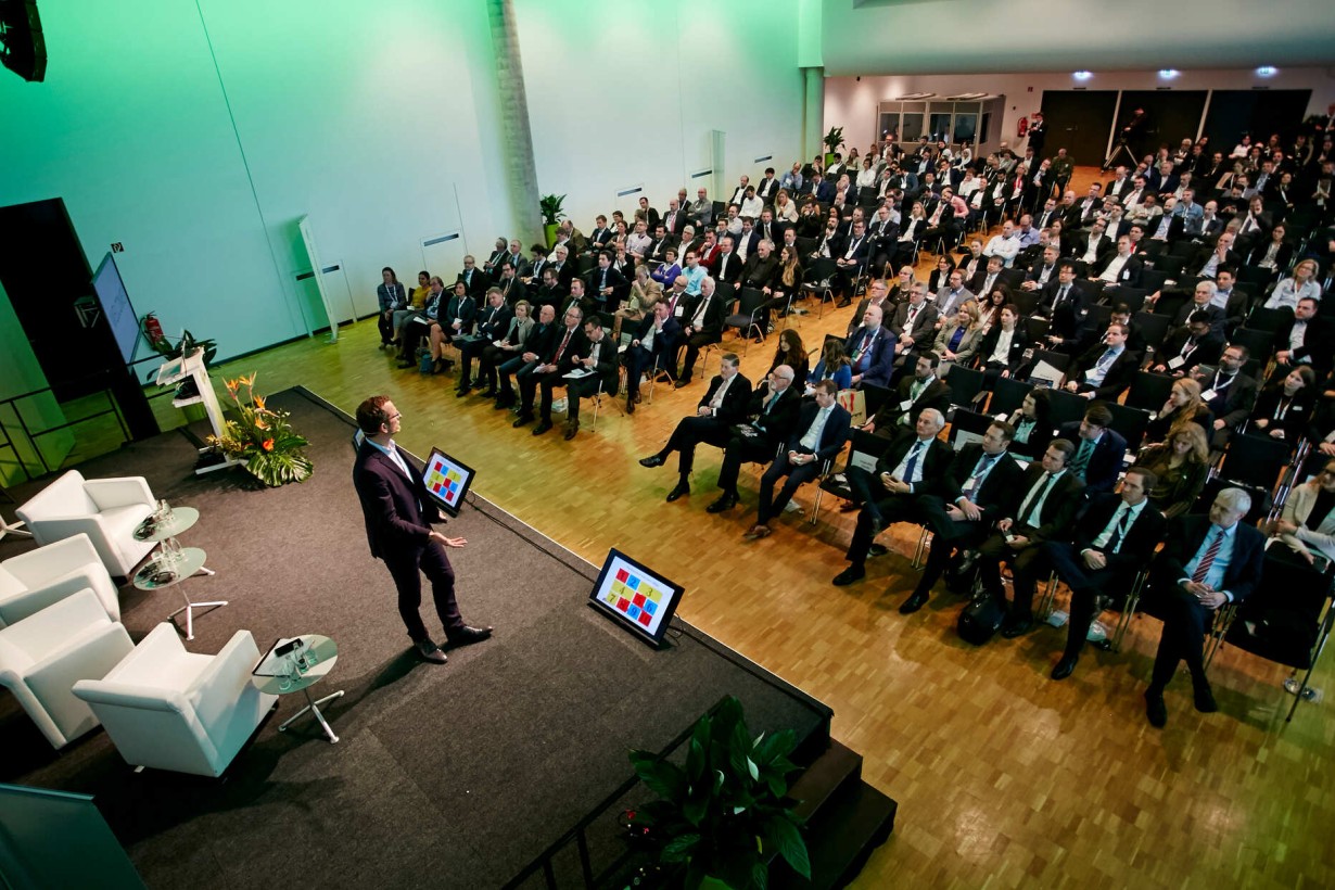 Symbolbild eines Kongress, wo ein Speaker einen Vortrag vor einem Fachpublikum hält. 