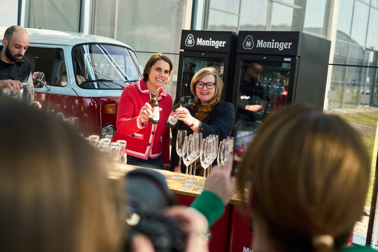 Dorothee Scheidtweiler und Britta Wirtz stoßen mit zwei Flaschen Moninger Bier an. 