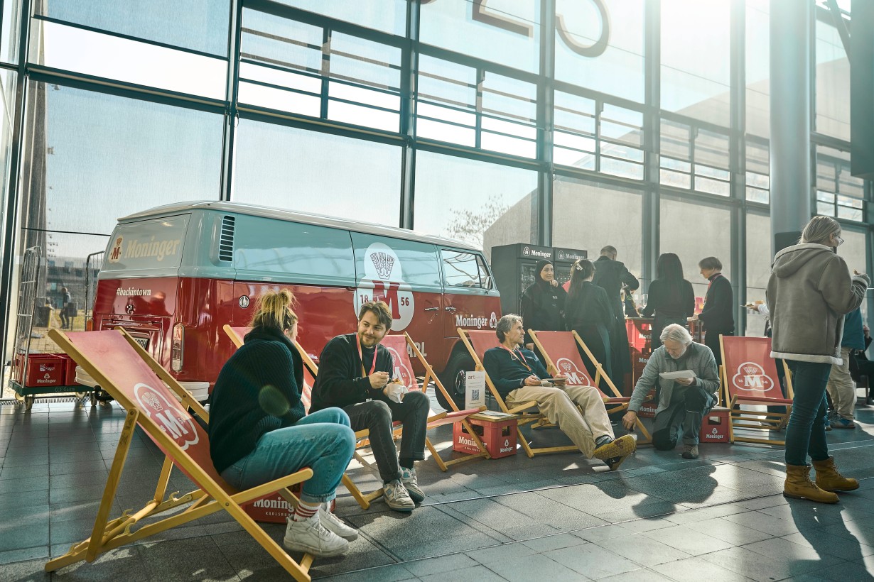 Vor dem Moninger Bus sitzen Besuchende der Messe auf Strandstühlen und unterhalten sich. 