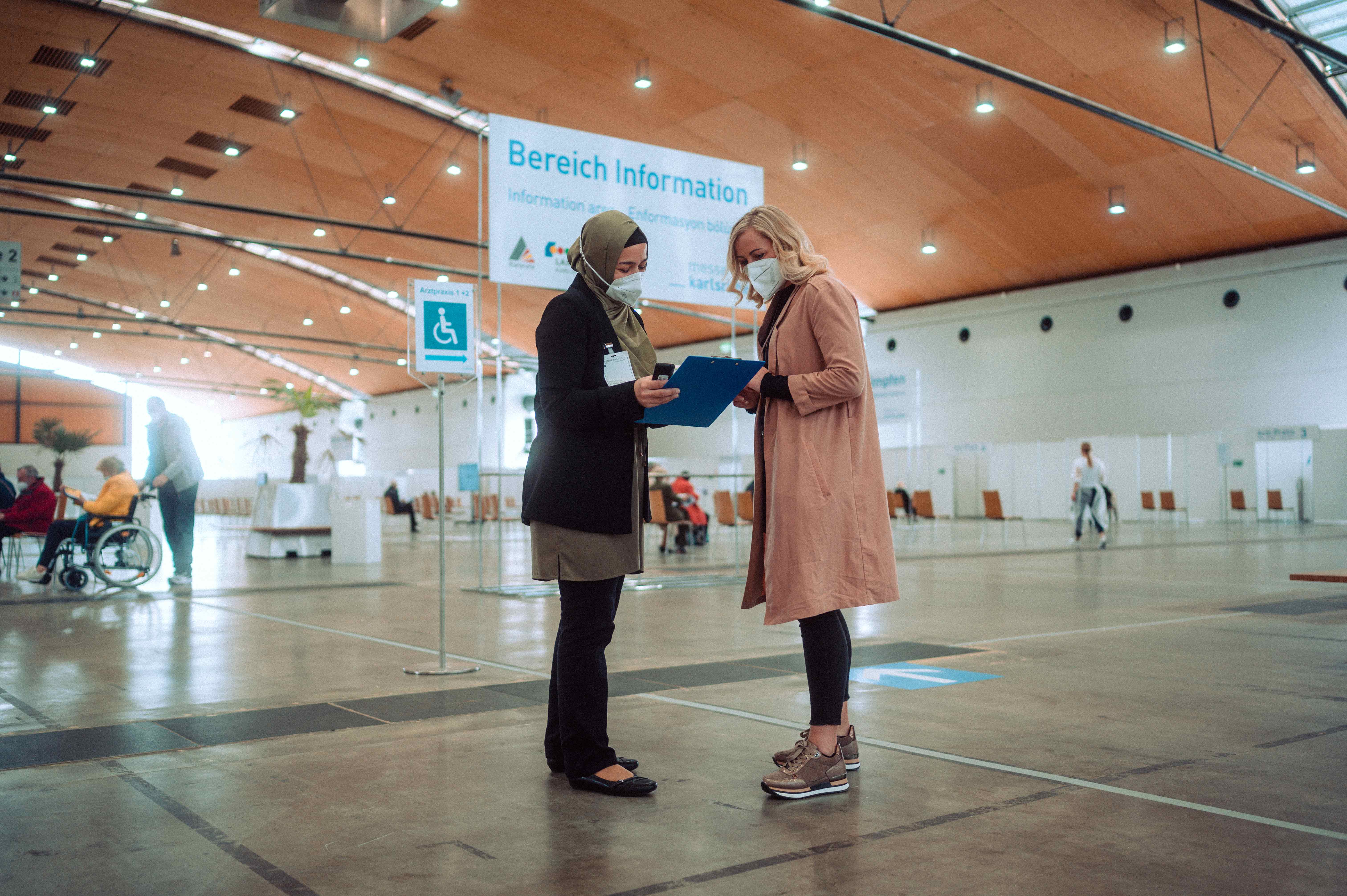 Zwei Mitarbeiterinnen der Messe führen ein Gespräch Messe Karlsruhe als Impfstandort