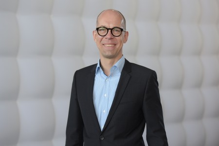 A man standing vor a white wall