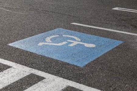 A blue square with a wheelchair icon has been spray-painted on a parking lot. 